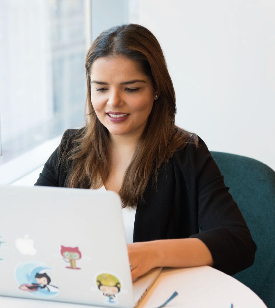 Mujer sonriendo trabajando con su laptop en un ambiente cálido y luminoso